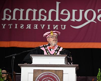 President Jonathan Green stands at a podium dressed in his academic regalia.